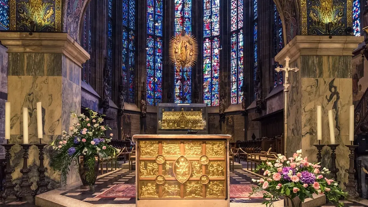 Wnętrze katedry z ołtarzem i witrażami. Wzrok przyciąga złota szkatuła, przypominająca o treści psalmu 137.