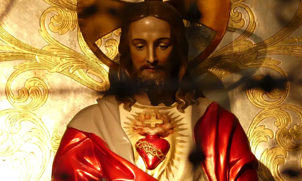 Figurka Jezusa z Sercem, symbolizująca uroczystość Najświętszego Serca Pana Jezusa, na tle złoconych ornamentów.