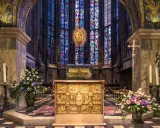 Wnętrze katedry z ołtarzem i witrażami. Wzrok przyciąga złota szkatuła, przypominająca o treści psalmu 137.