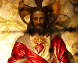Figurka Jezusa z Sercem, symbolizująca uroczystość Najświętszego Serca Pana Jezusa, na tle złoconych ornamentów.