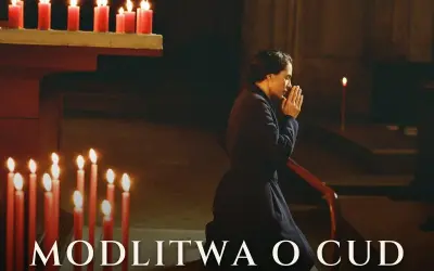 Kobieta klęczy w kościele, dłonie złożone do modlitwy. Płoną świece, tworząc atmosferę nadziei i modlitwy o cud.