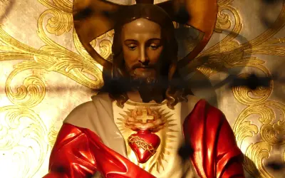 Figurka Jezusa z Sercem, symbolizująca uroczystość Najświętszego Serca Pana Jezusa, na tle złoconych ornamentów.