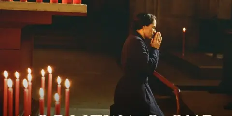 Kobieta klęczy w kościele, dłonie złożone do modlitwy. Płoną świece, tworząc atmosferę nadziei i modlitwy o cud.