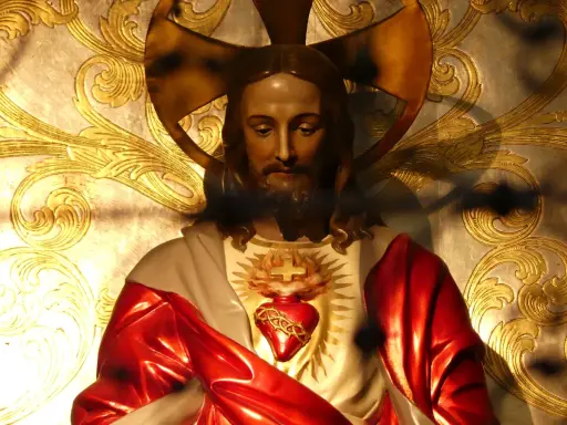 Figurka Jezusa z Sercem, symbolizująca uroczystość Najświętszego Serca Pana Jezusa, na tle złoconych ornamentów.