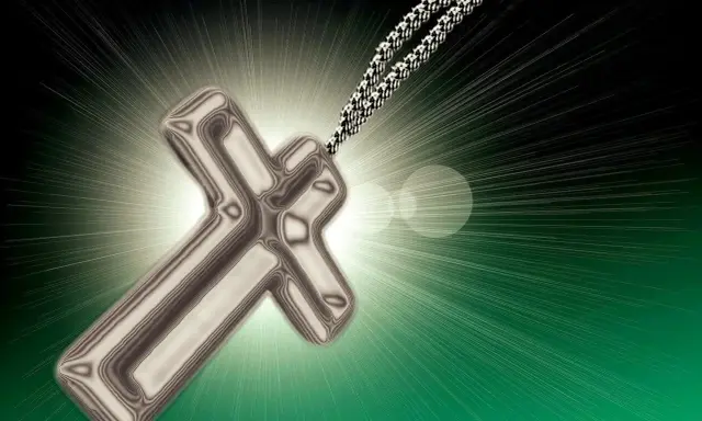 Srebrny krzyż na łańcuszku, symbol wiary, jak tekst psalmu 62, rozświetla mrok.